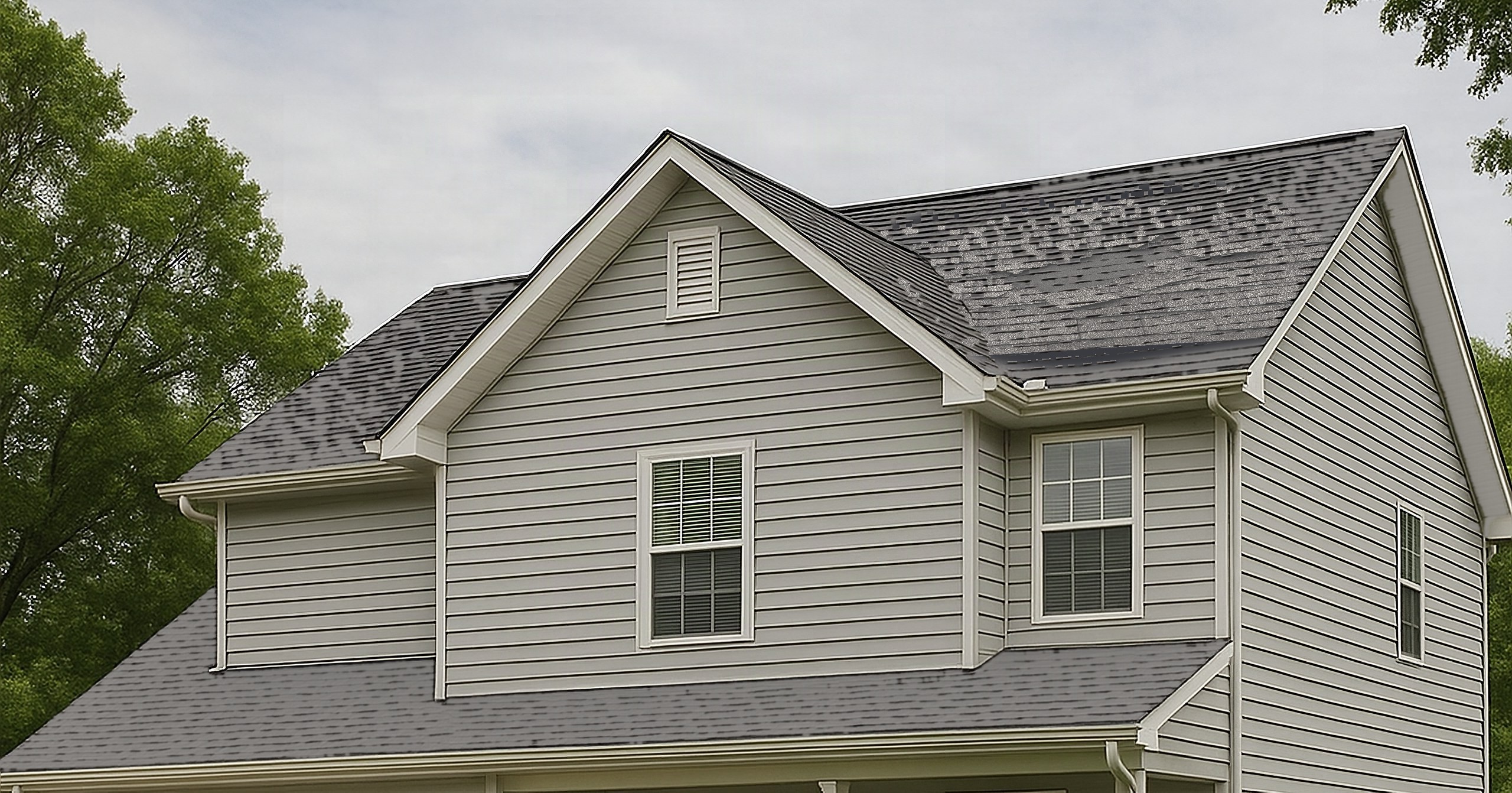 Illustrative example: a Knoxville-area home after a windstorm, with a torn-off patch of shingles on the main roof plane exposing the dark underlayment and several lifted shingle tabs along its edge